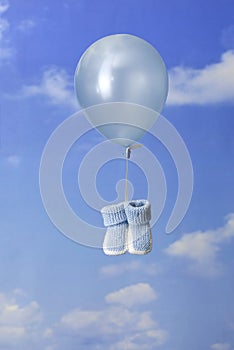 Birth concept: balloon carrying blue baby booties