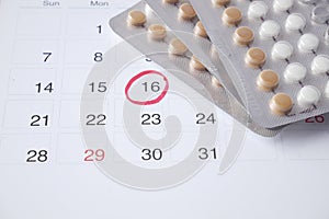 birth control pills , calendar and notepad on table