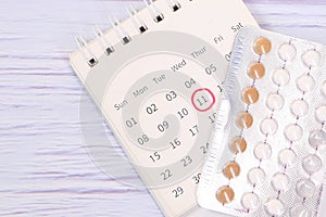 Birth control pills , calendar and notepad on table