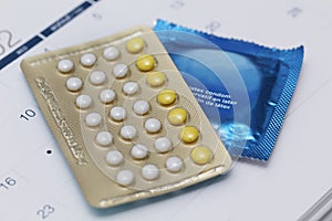 Birth control pills with condom on a calendar