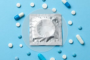 Birth control pills and condom in package on blue. The concept of choosing method of contraception, birth control pills or condom