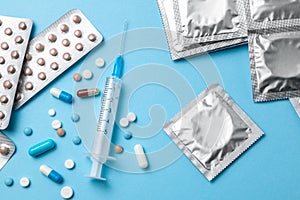 Birth control pills, an injection syringe and condom in a package on blue. The concept of choosing method of contraception