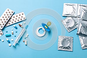 Birth control pills, an injection syringe and condom in a package on blue. The concept of choosing method of contraception