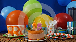Birthday 25 cake on rustic wooden table with background of colorful balloons, gifts, plastic cups, plastic plate