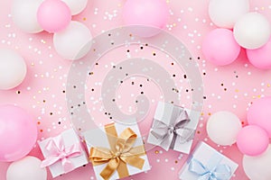 Birthday background with gift or present box, balloons and confetti on pink pastel table top view. Flat lay.