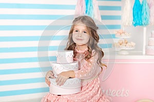 Birthday! Beautiful little girl sitting with gifts. Candy`s birthday bar. Portrait of a baby face closeup. Little cute girl playin