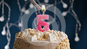 Birthday cake with 5 number pink candle on blue backgraund. Candles are set on fire