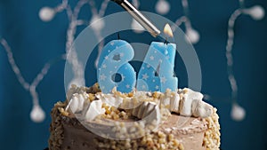 Birthday cake with 64 number candle on blue backgraund. Candles are set on fire