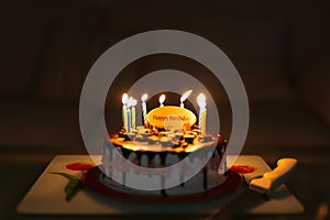 Birthday cake on black background with colorful candles lit.