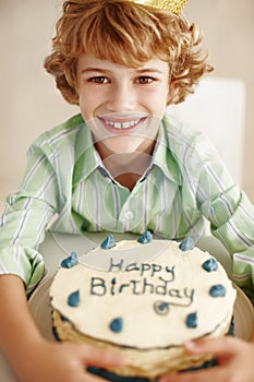 Birthday cake, boy and happy in portrait at table in family home for celebration, growth and memory. Child, dessert and