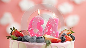 Birthday cake candle number 64. Candle and cake on pink background and fire by lighter. Close-up and slow motion