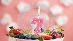 Birthday cake candle number 7. Candle and cake on pink background and fire by lighter. Close-up and slow motion
