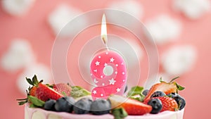 Birthday cake candle number 9. Candle and cake on pink background and fire by lighter. Close-up and slow motion