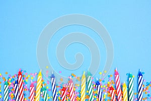 Birthday cake candles with candy sprinkles. Bottom border on a blue background.