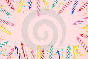 Birthday cake candles with candy sprinkles frame on a pink background