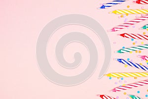 Birthday cake candles with candy sprinkles side border on a pink background