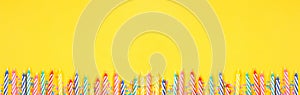 Birthday cake candles with candy sprinkles. Banner with bottom border on a yellow background. photo