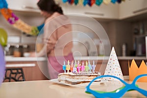 Birthday cake with candles standing at the table with another party decorations nearby