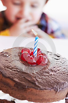 Birthday cake closeup, young kid and celebration candle with dessert at home with a child. Chocolate, cherry and candles