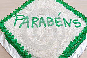 Birthday cake decorated with green icing and grated coconut. Isolated on wooden table background