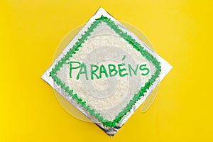 Birthday cake decorated with green icing and grated coconut. Isolated on yellow background. Top view photo