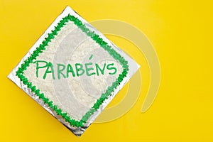 Birthday cake decorated with green icing and grated coconut. Isolated on yellow background photo