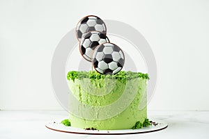 Birthday cake for a football fan with green cream cheese frosting, grass and soccer balls gingerbread cookies on top