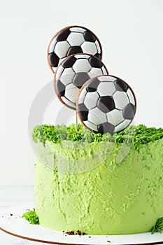 Birthday cake for a football fan with green cream cheese frosting, grass and soccer balls gingerbread cookies on top