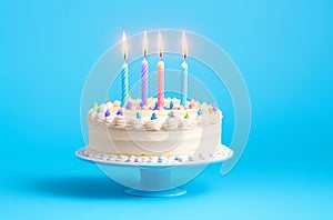 Birthday Cake with Four Candles on a Pastel Blue Background and Copy Space.