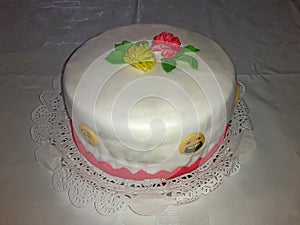 Birthday cake glazed, white, red, green and yellow decoration, placed on a paper tray