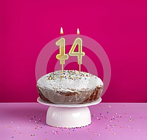 Birthday cake with number 14 candle on pink background
