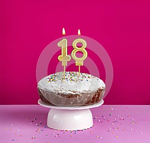 Birthday cake with number 18 candle on pink background