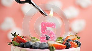 Birthday cake number 5, pink candle on beautiful cake with berries and lighter with fire against background of white