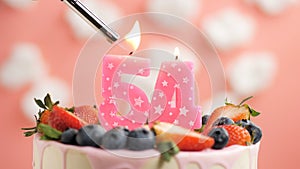 Birthday cake number 54, pink candle on beautiful cake with berries and lighter with fire against background of white