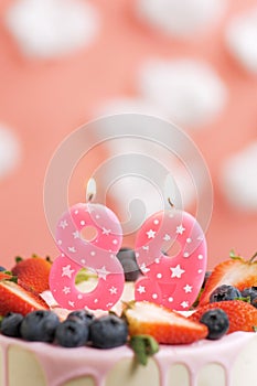 Birthday cake number 89. Beautiful pink candle in cake on pink background with white clouds. Close-up and vertical