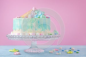 Birthday cake in pastel colors, marshmallow and candies on pink background, selective focus