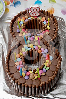 Birthday cake in the shape of a number eight, made from chocolate buttons, smarties and chocolate finger biscuits