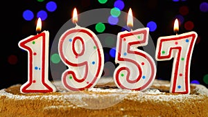 Birthday cake with white burning candles in the form of number 1957