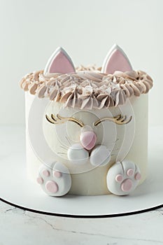 Birthday cake with white cream cheese frosting decorated with mastic cat ears, paws and face.