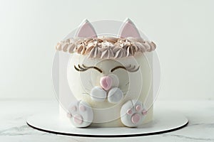 Birthday cake wth white cream cheese frosting decorated with mastic cat ears, paws and face. Surprise cake for a little girl on