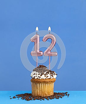 Birthday candle with cupcake on blue background - Number 12