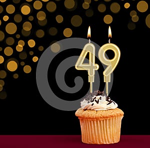 Birthday candle with cupcake - Number 49 on black background with out of focus lights