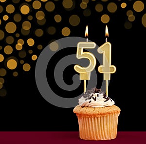 Birthday candle with cupcake - Number 51 on black background with out of focus lights
