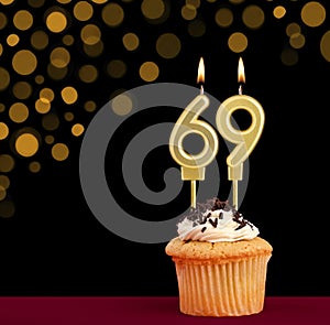 Birthday candle with cupcake - Number 69 on black background with out of focus lights