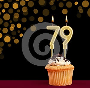 Birthday candle with cupcake - Number 79 on black background with out of focus lights