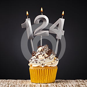 Birthday candle number 124 - Anniversary cupcake on black background