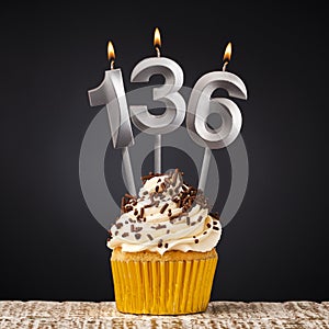 Birthday candle number 136 - Anniversary cupcake on black background