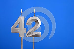 Birthday candle number 42 - Celebration card on blue background