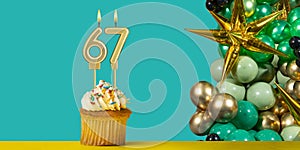 Birthday candle number 67 - Cupcake with decoration on a green background
