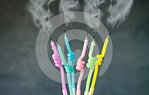 Birthday candles with flame blown out smoke on dark background